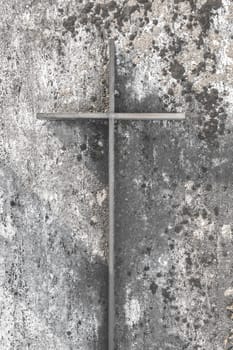 Iron christian cross on an old concrete wall
