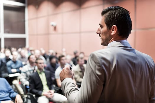 Speaker giving a talk on corporate business conference. Unrecognizable people in audience at conference hall. Business and Entrepreneurship event.