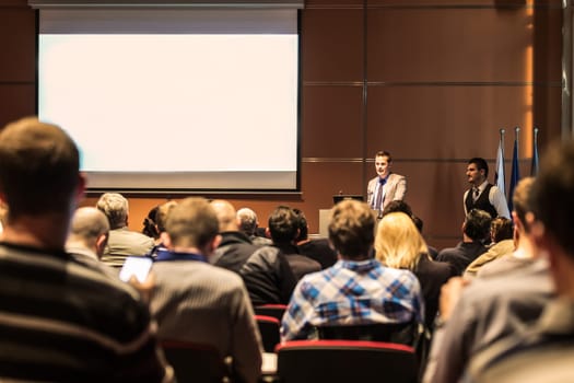 Speaker giving a talk in conference hall at business meeting event. Rear view of unrecognizable people in audience at the conference hall. Business and entrepreneurship concept.