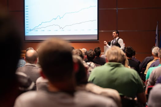 Speaker giving a talk in conference hall at business meeting event. Rear view of unrecognizable people in audience at the conference hall. Business and entrepreneurship concept.