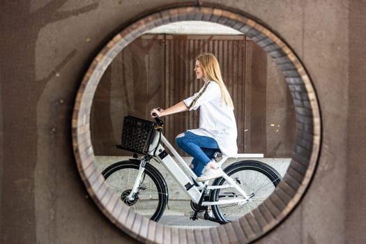 Casual caucasian teenager riding urban electric bicycle in urban environment. Urban mobility concept.