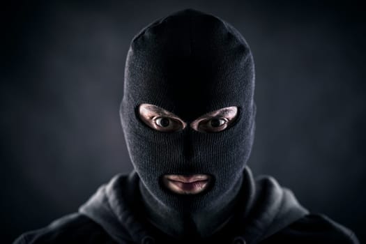Criminal wearing black balaclava and hoodie in the dark