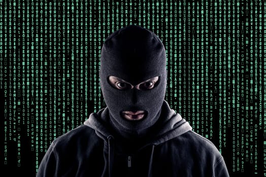 Masked cyber terrorist with black balaclava and hoodie in the dark