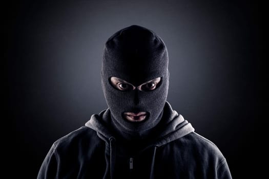 Criminal wearing black balaclava and hoodie in the dark