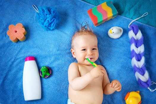 one year old baby lying on towel with washing tools