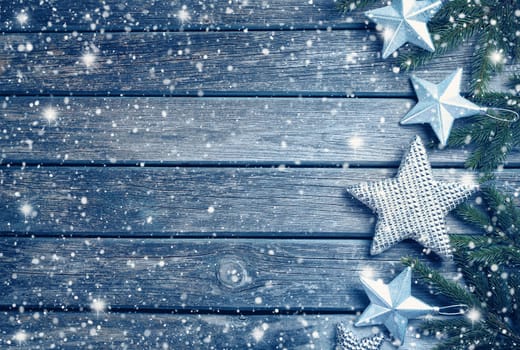Christmas stars on wooden background with fir tree branches. Winter background