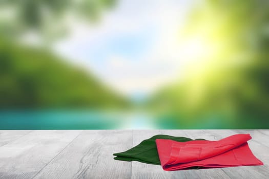 Empty table product. Closeup of a empty red and green tablecloth or napkin on a bright table over abstract blurred colorful natural background. Template for your food and product display montage.