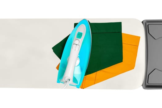 Top view of a modern electric blue iron ironing a green and a yellow cloth napkin on an ironing board indoors isolated. Advertising for the laundry service with space.