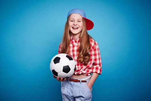 Smiling girl keeping soccer ball in her hands