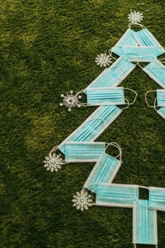 Christmas Tree Made of Blue Medical Masks on a Green Background With Copy Space
