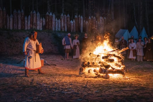 Cedynia, Poland, June 2019 Pagan reenactment of Kupala Night, called in Poland Noc Kupaly, shaman in wooden mask pouring grain to fire. Slavic holiday celebrated on the shortest night of the year