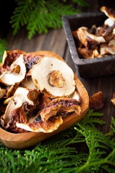 Dehydrated penny bun, boletus edulis mushrooms in a wooden bowl with a green spruce twigs. Vertical image