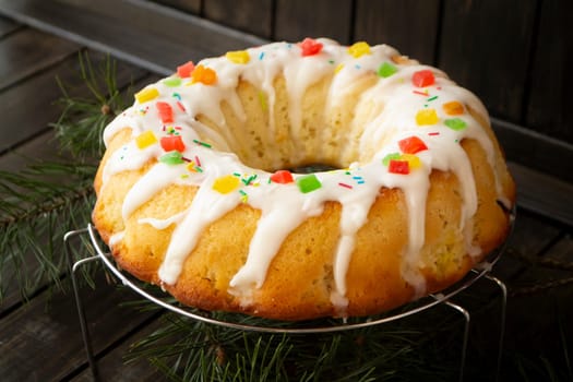 Candied berries bundt cake with lemon sugar glaze on wooden table. Homemade autumn and winter cozy holiday dessert