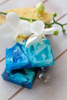 Natural handmade soap in blue water color with white orchid, vertical image