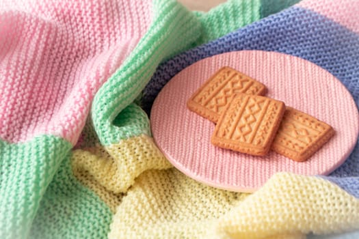 Golden cookies with knitted effect scattered on a knitted blanket. romantic mood concept. Christmas life style