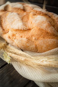 Freshly baked multi grain bread on rustic dark wooden background. Low key still life with directional natural lighting, vertical image