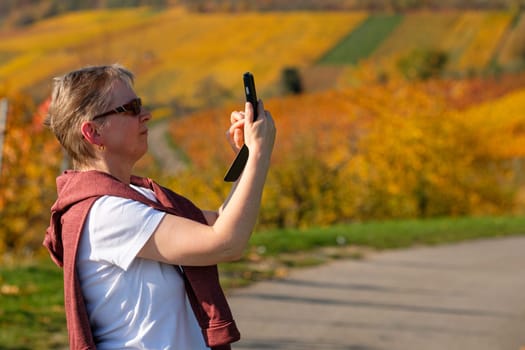 Woman is tipping on her smartphone in autumn landscape