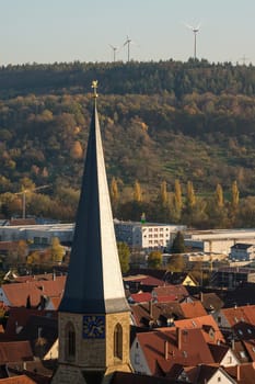 Christian church steeple with wind power plant in background