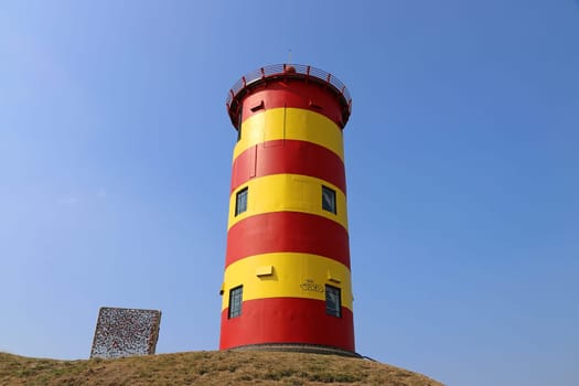 The red and yellow Pilsum lighthouse on the East Frisian North Sea coast in Germany