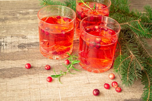 Christmas glasses of red hot mulled wine ore compote of cowberries with spices and cowberries surrounded by fir branches