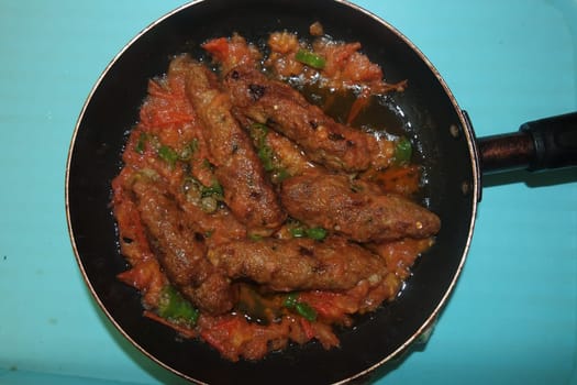 Closeup view of delicious spicy home made fried kebab with green mint leaves and green pepper sprinkled on it