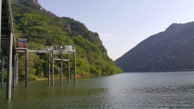 View of beautiful scene of river water and green trees on large hills on a sunny day with blue sky in background. A lovely landscape with breathtaking view over the horizon .