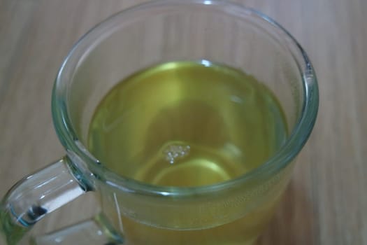 Glass cup having brewed fragrant green tea or qehwa or qahwa on the wooden floor. It is served with sugar or honey and nuts