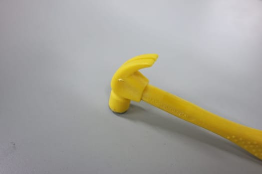 Selective focused, closeup view of toy hammer made from plastic placed on metal background