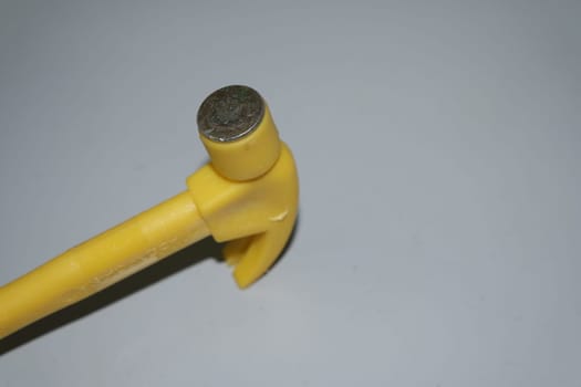 Selective focused, closeup view of toy hammer made from plastic placed on metal background