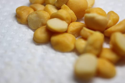 Yellow chickpea lentils seeds macro closeup view. Chana daal or yellow split peas on white blurred background