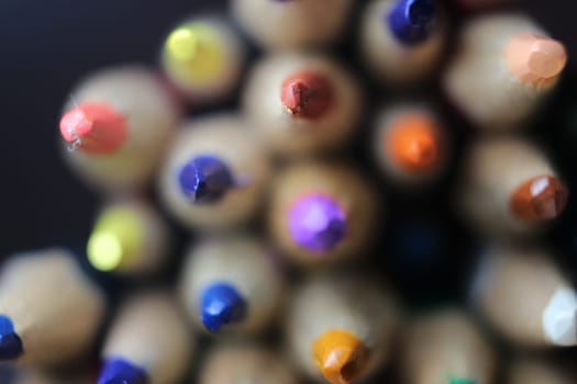 Close-up view of bright colored multicolor pencils on black background