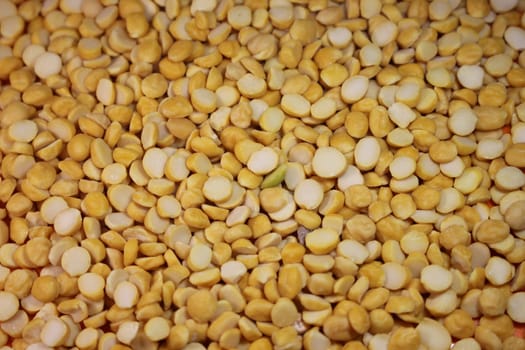 Yellow chickpea lentils seeds macro closeup view. Chana daal or yellow split peas spread background