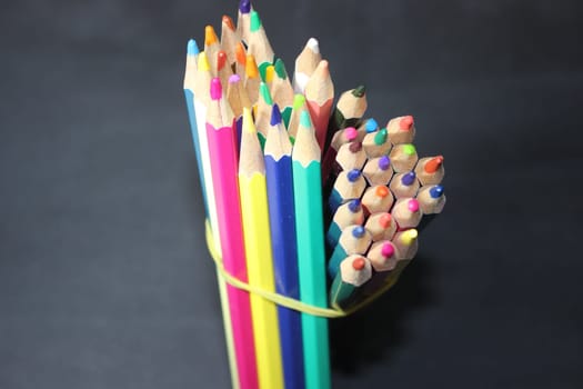 Close-up view of bright colored multicolor pencils on black background