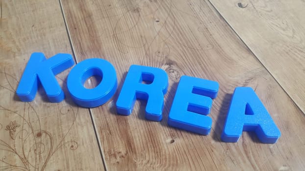 Plastic colored alphabets making words October are placed on a wooden floor. These plastic letters can be used for teaching kids.