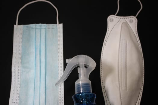 blue color cloth face mask with hand sanitizer bottle isolated on black background