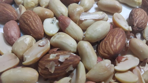 Closeup view of mixed dried and roasted  peanuts and almonds. A fruit for background text