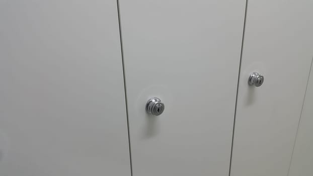 Perspective view of lockers or cupboards in a row with white doors, keys and locks