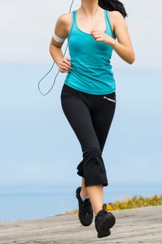 Beautiful young woman jogging on a boardwalk and listen music