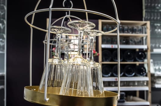 Empty new wine glasses hanging over golden tray. Selective focus