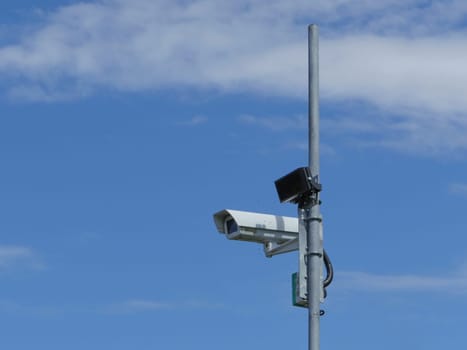 Surveillance camera on a pole high in the blue sky