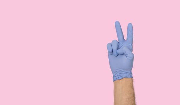Hands gestures. human hand in latex glove showing fingers in the air symbol isolated on pastel pink background with copy space. irony, sarcasm concept