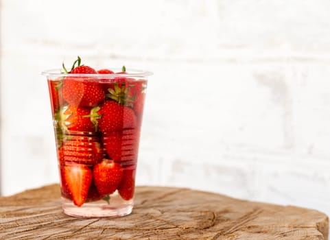 Organic red strawberries glass and mint leaves on rustic wooden background.