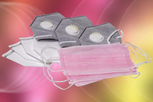Close-up of grey and white N95 face masks and pink medical face masks against abstract pastel background. Space for design such as New Normal, Lifestyle 2021, coronavirus, lockdown or other.