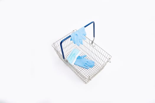 Shopping basket with hand gloves and mouth mask, isolated on white background