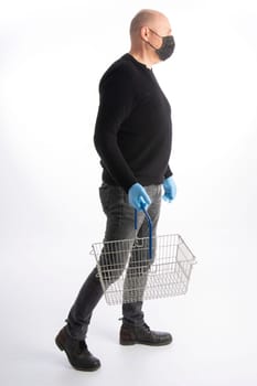 Man with mouth protection and hand gloves carrying a shopping basket, isolated on white background