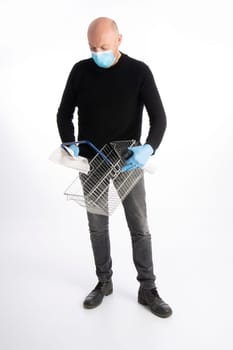 Man with mouth protection and hand gloves cleaning a shopping basket, isolated on white background