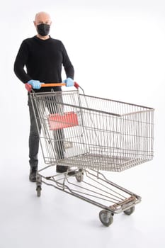 Man with mouth protection and hand gloves pushing a shopping cart, isolated on white background
