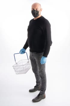 Man with mouth protection and hand gloves carrying a shopping basket, isolated on white background
