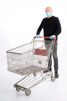 Man with mouth protection and hand gloves pushing a shopping cart, isolated on white background