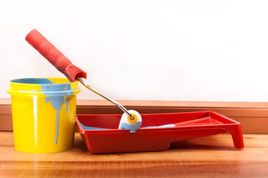 Yellow bucket of blue paint and a roller for painting walls